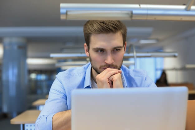 How to make money on traffic arbitrage: a full guide for beginners young man using laptop sitting thinking his desk as he reads information screen 484651 4619 - How to make money on traffic arbitrage: a full guide for beginners